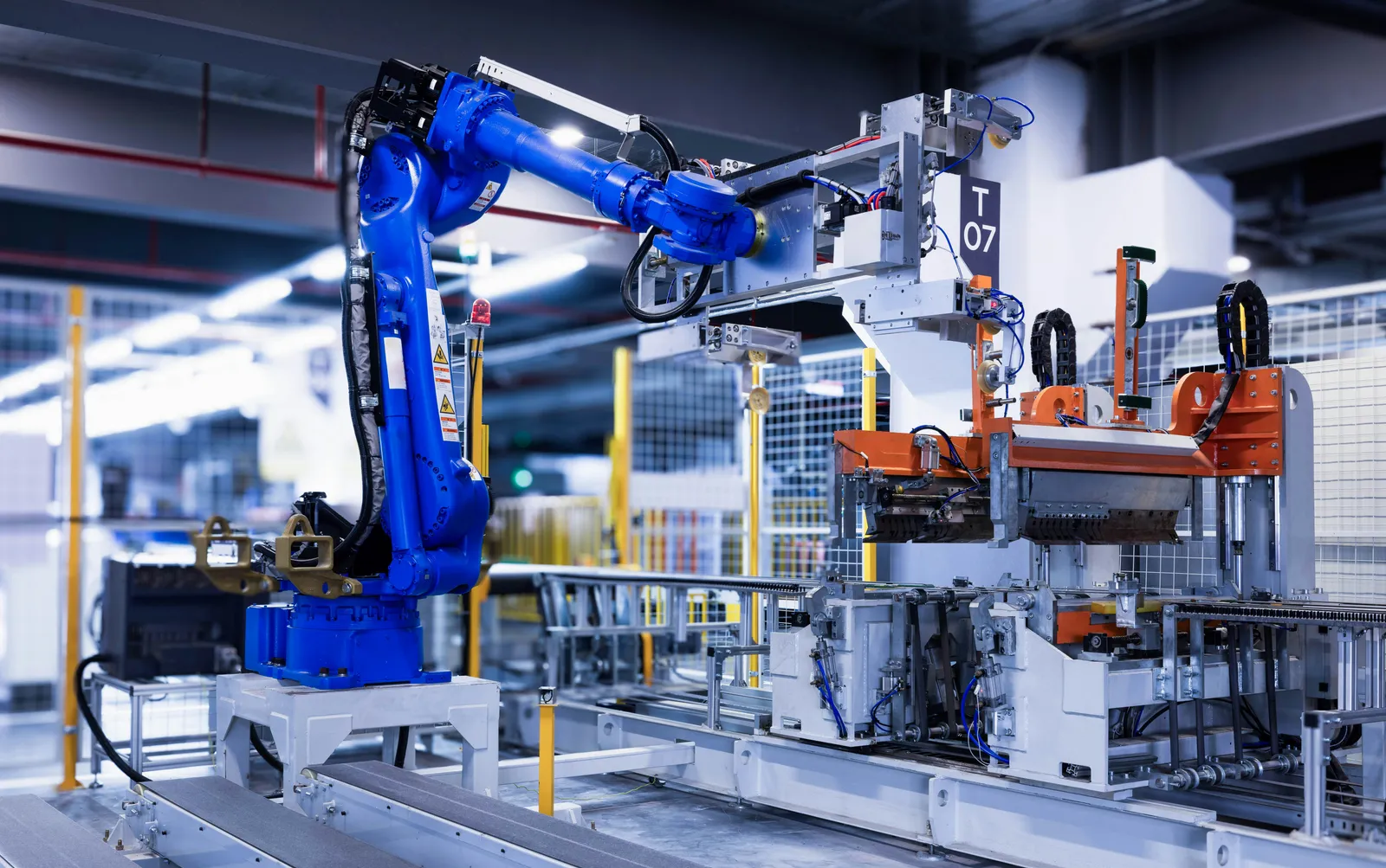 Niebieskie ramię robota przemysłowego na hali produkcyjnej
