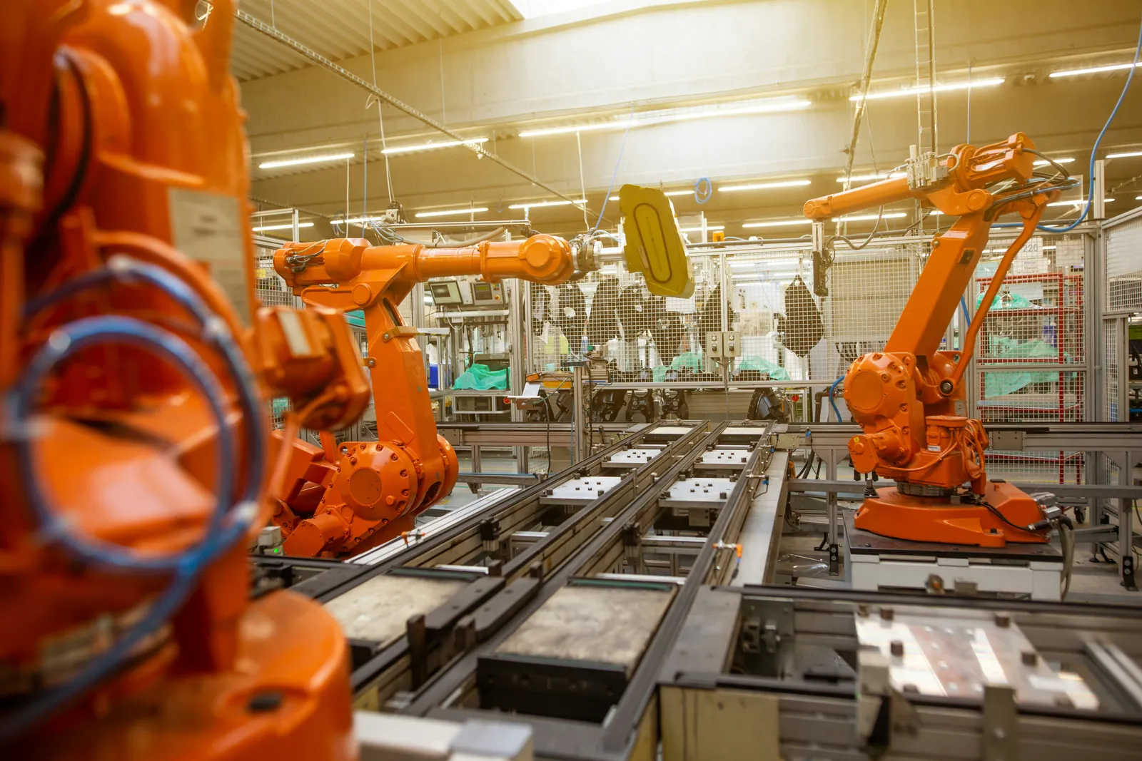 Pomarańczowe ramiona robotów przy linii montażowej w hali produkcyjnej